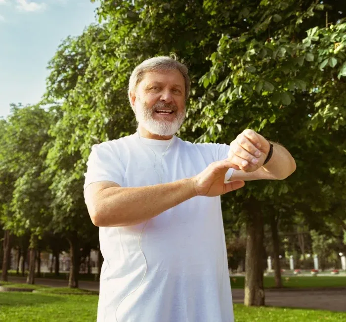 An older man outdoors checking the time on his wristwatch
